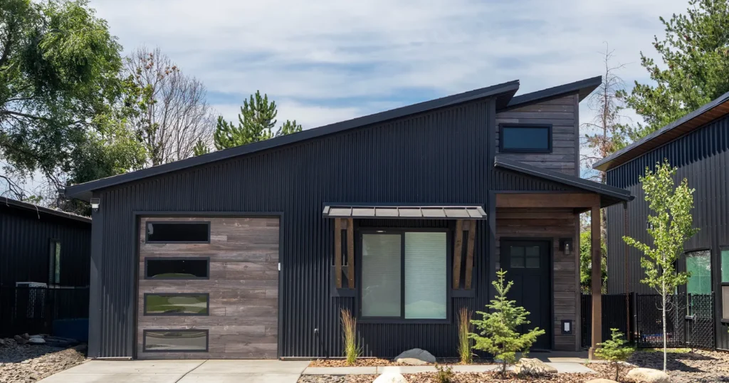 A kit home with a garage. Black home and custom woodgrain garage door from Kit Culture