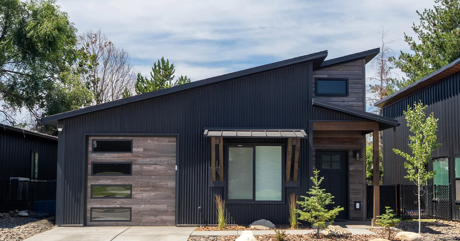 A kit home with a garage. Black home and custom woodgrain garage door from Kit Culture