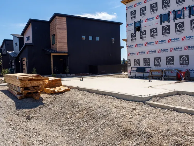 Lumber staged at a prepared foundation site, the kind of site work that sits outside prefab homes prices